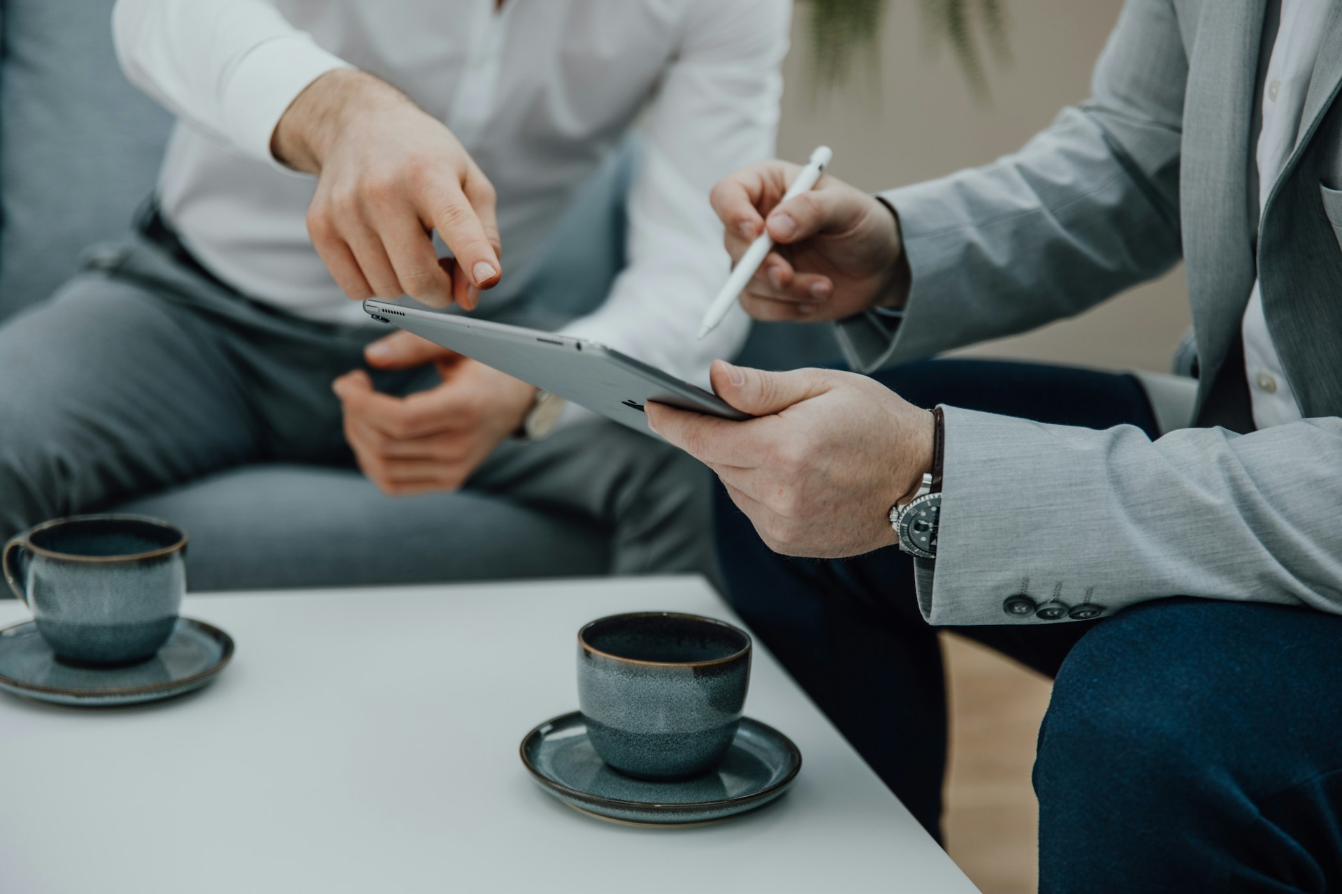 Two people sit at a table with a tablet